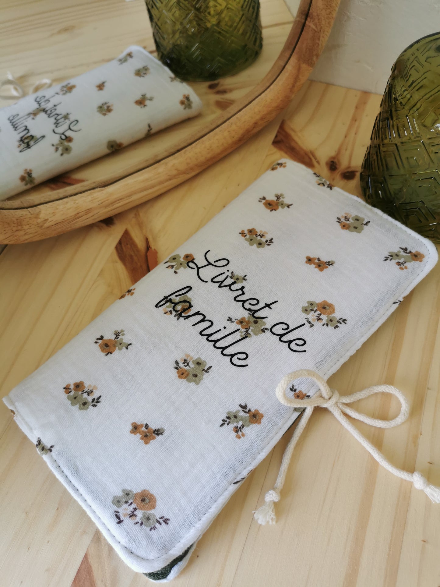 Un livret de famille bicolore, texte "Livret de famille" en application textile, fermeture à noeud, tissu principal DG petites fleurs et tissu secondaire DG vert forêt