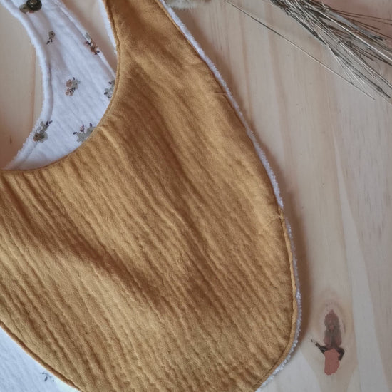 Vidéo d'un coffret de naissance en double gaze jaune moutarde, fleurs, composés de bavoirs, lingettes lavables et langes